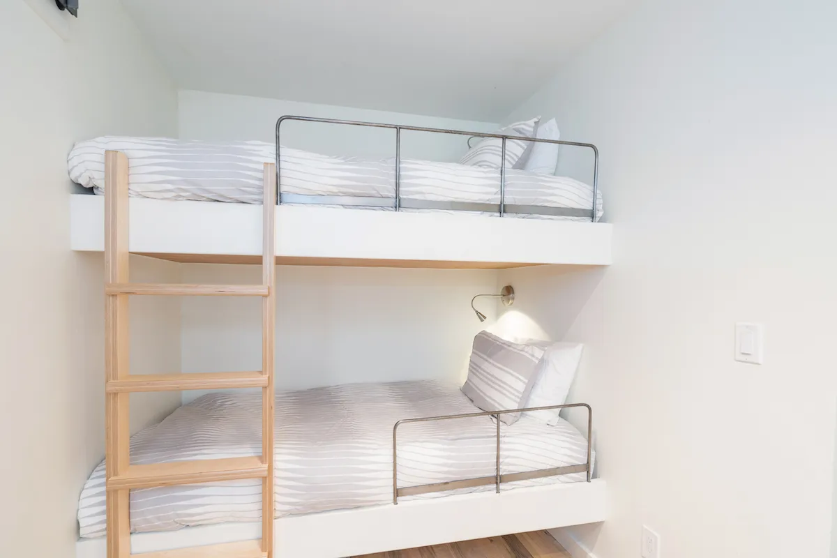 A cozy bunk bed nook with wooden ladders and striped bedding, exuding warmth and playful comfort. The layout suggests a family-friendly space designed for both relaxation and bonding, with thoughtful touches that make guests feel at home.